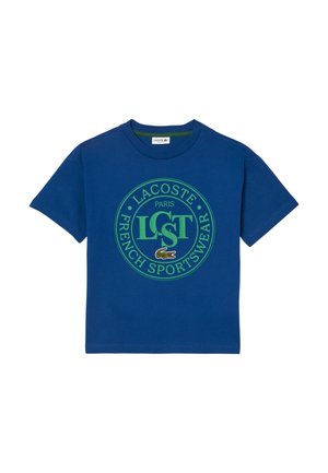 Blå kortærmet T-shirt med grønt rundt Lacoste Paris French Sportswear-logo og lille broderet krokodilleemblem centreret på brystet.