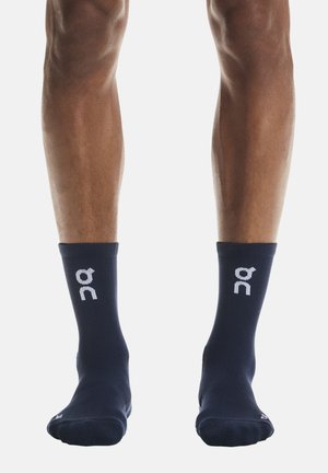 Calzini da caviglia blu navy realizzati in materiale traspirante, con un logo bianco sulla caviglia e una vestibilità aderente per comfort e supporto durante l'attività.