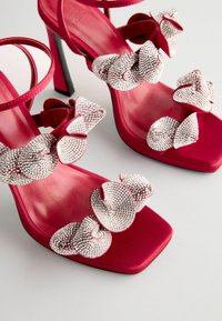 Fuchsia High-Heelsandalen mit quadratischer Zehenpartie, verziert mit aufwendigen silberfarbenden Strassschleifen und einer glatten Satinoberfläche.