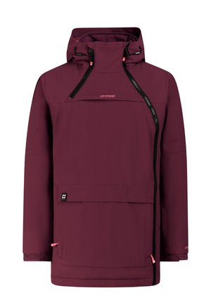 Jong persoon die een winteroutfit draagt met een kastanjebruine jas, felroze broek, zwarte handschoenen, zwarte laarzen en een beige gebreide muts met kastanjebruine strepen.
