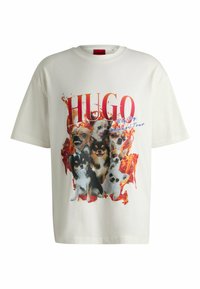 T-shirt bianca a maniche corte con una stampa grafica di diversi cani, circondati da un effetto infuocato, con "HUGO" ben visibile.