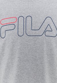 Camiseta de algodón gris con el logotipo "FILA" en azul marino y un acento rojo encima de la letra "F", escote redondo y mangas cortas.