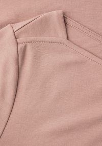 Nahaufnahme von gefaltetem, weichem rosa Stoff mit ordentlicher Naht und gestrickter Textur.