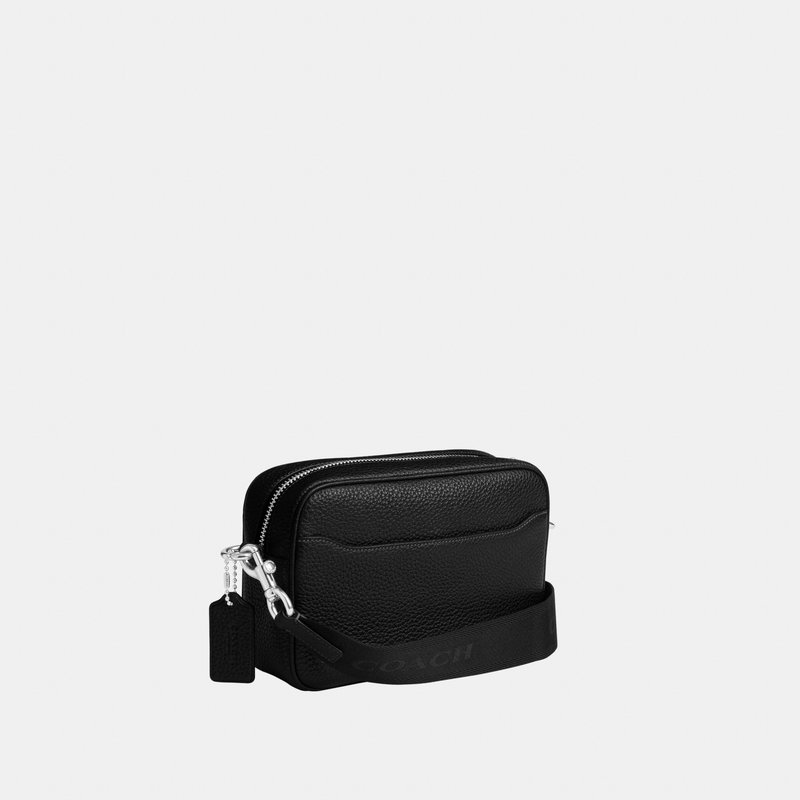 Bolso bandolera compacto de piel negra con acabado texturizado, cremallera plateada, correa desmontable y etiqueta de marca adherida al lateral.