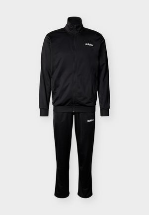 Fekete Adidas melegítő szett cipzáras dzsekivel és hozzáillő nadrággal, fehér Adidas logókkal a mellkason és a combnál.