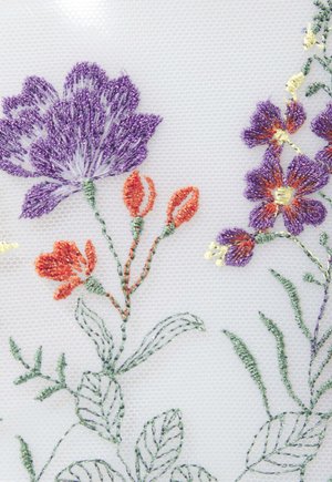 Besticktes Blumenmuster auf transparenter weißer Stoff. Enthält lila und orange Blumen mit grünen Blättern und zeigt aufwendige Stickerei und Textur.