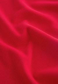 Tessuto rigato e texturizzato di un brillante rosso, che presenta una superficie morbida e liscia con un motivo ondulato, enfatizzando la sua elasticità e profondità.