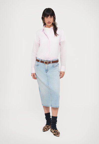 Ανοιχτό ροζ πουκάμισο με κουμπιά, τζιν φούστα μεσαίου μήκους, καφέ ζώνη, μπλε κάλτσες και παπούτσια με animal print. Απλή, καθημερινή εμφάνιση με στρωματοποιημένες υφές.