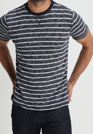 T-shirt rayé bleu marine et blanc avec un col rond, des manches courtes et un tissu texturé. Design simple et décontracté sans logos visibles.