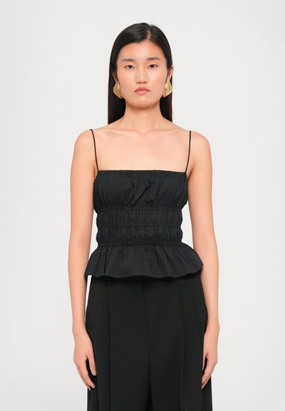 Schwarzes Peplum-Oberteil mit dünnen Trägern, gerafftem Oberteil und einem rüschenden Saum. Glattes Gewebe mit dezentem Glanz, kombiniert mit hoch taillierten schwarzen Hosen.