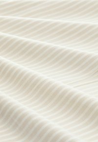 Cream fabric with horizontal wavy stripes. Material appears soft and smooth, showcasing a subtle texture in a light neutral color palette.
