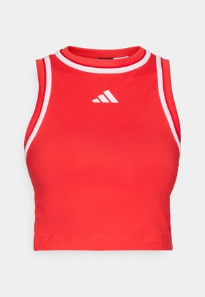 Rdeč kratki top z okroglim izrezom, narejen iz elastičnega materiala, z belimi obrobami in logotipom Adidas na sprednji strani.
