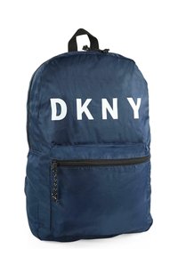 Mochila de nylon azul marino con gran logo blanco "DKNY", bolsillo frontal con cremallera, asa superior y detalles en cremallera negra. Textura suave y diseño simple.