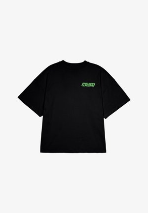 Fekete, oversize pamut póló, rövid ujjakkal, zöld logóval a bal mellkason. Egyszerű, kerek nyakkivágású kialakítás.