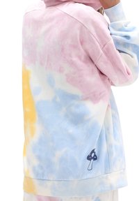 Felpa con cappuccio tie-dye pastello nei colori rosa, giallo e blu, con una consistenza morbida. Presenta una piccola grafica di fungo sull'orlo inferiore.