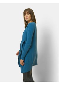 Blauwe gebreide cardigan met een ontspannen pasvorm, lange mouwen en geribbelde manchetten. Het ontwerp heeft een open voorkant en een zachte textuur.