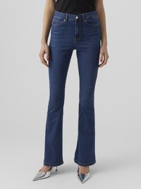 Sinine denimist laienevad teksad kõrgema taljega, viiega taskut ja puhta viimistlusega. Kanda metallik hõbedast kõrge kontsaga kingadega.