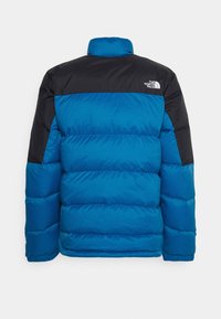 Niebieska kurtka puchowa z czarnymi akcentami, z wysokim kołnierzem i poziomym pikowaniem. Logo marki jest umieszczone na górnej części pleców.