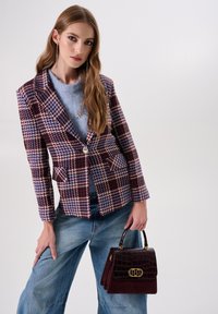 Gestructureerde geruite blazer in bordeauxrood, blauw en crèmekleurig met een enkele knoop en zakken; gecombineerd met een lichtblauwe trui en een bordeauxrode krokodillenleren tas.