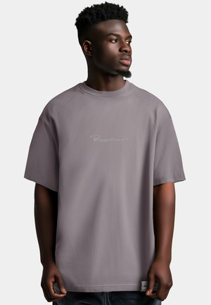 Maglietta oversized grigia con maniche corte, caratterizzata da un collo a girocollo a coste e un logo ricamato sul davanti. Tessuto liscio con orlo dritto.