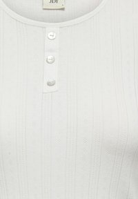 Biały prążkowany top z okrągłym dekoltem, ozdobiony trzema guzikami przypominającymi perły oraz subtelnymi, teksturowanymi wzorami na całej powierzchni.