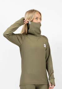 Olive green long-sleeve top with a high neck, made of ribbed texture fabric. Features a small brand label on the chest.