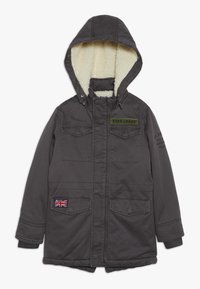 Ciemnoszara kurtka z podszyciem z imitacji baranka, regulowanym kapturem, zieloną etykietą i naszywką z flagą Wielkiej Brytanii. Posiada dwie kieszenie na piersi oraz ściągacze przy rękawach.