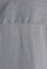 Tessuto tessile con motivo strutturato caratterizzato da fili intrecciati grigi e bianchi, creando un effetto a strisce sottili. Design di tessitura resistente.