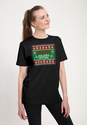 Sort T-shirt med et ferietema grafisk design i røde og grønne farver, snefnug, træer og teksten "GOTG Holiday Special."