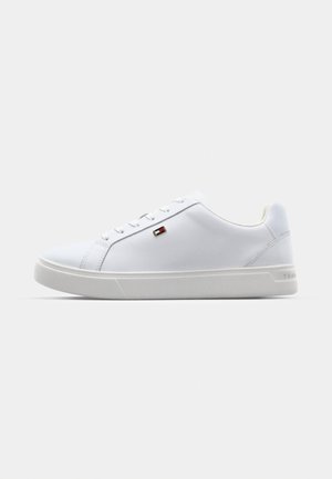 Vit sneaker med en slät syntetisk ovandel, rund tå, snörningsdesign och diskret logotypdetalj på sidan. Har en texturerad yttersula.