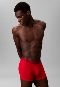 Boxer da uomo rossi di Calvin Klein con un cinturino marchiato nero. Il tessuto sembra liscio, aderente e elasticizzato con un design aderente.