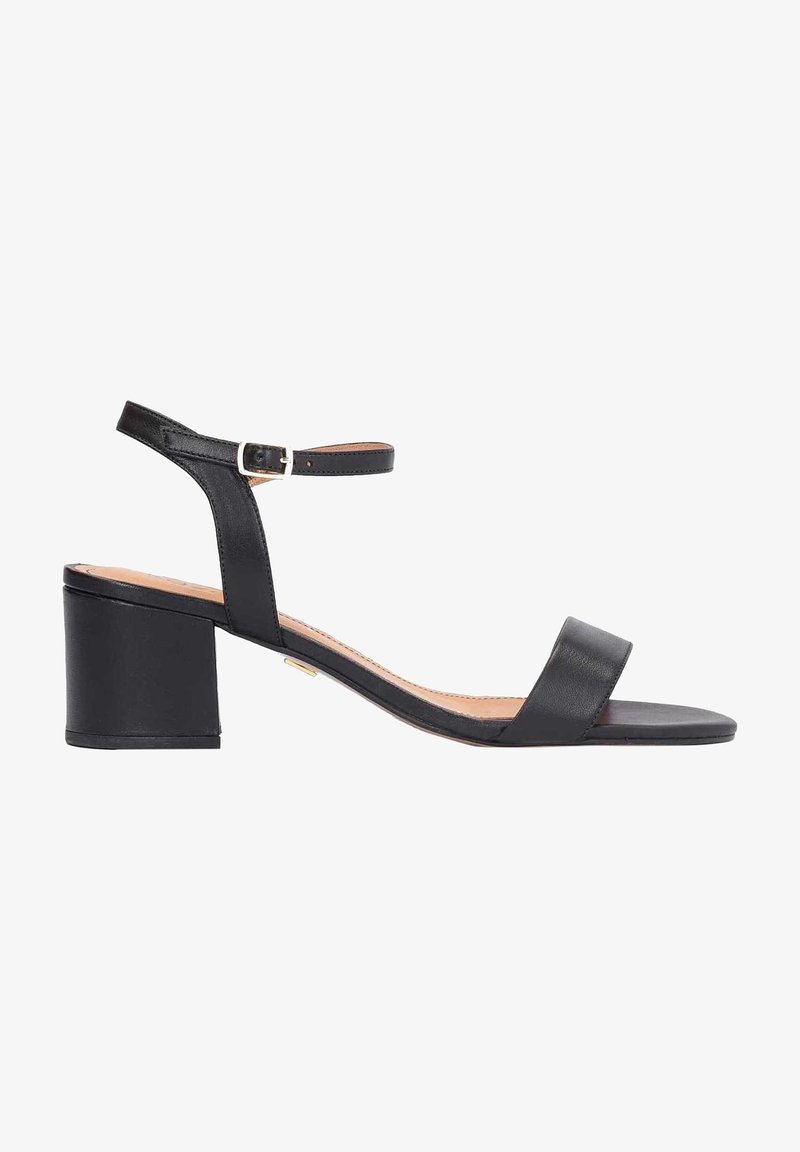 Sandale à talons en cuir noir avec un embout carré, une bride de cheville et un talon bloc. Texture lisse avec un design minimaliste et une accent en boucle métallique.