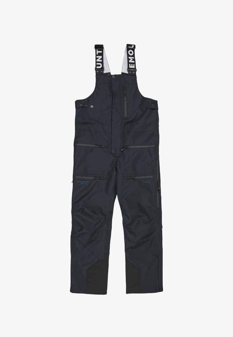 Salopette blu navy con spallacci regolabili, numerose tasche con zip, rinforzi neri sulle ginocchia e una texture del tessuto impermeabile.