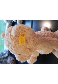 Hellbrauner Plüschbär mit weichem Fell, runden Ohren und einem kleinen gelben Anhänger mit Sicherheitszertifikat auf dem Rücken.