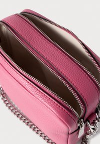 Ροζ δερμάτινη τσάντα χιαστί με τρεις θήκες με φερμουάρ, ασημένια μεταλλικά στοιχεία και λουρί αλυσίδα, με υφή επιφάνειας.