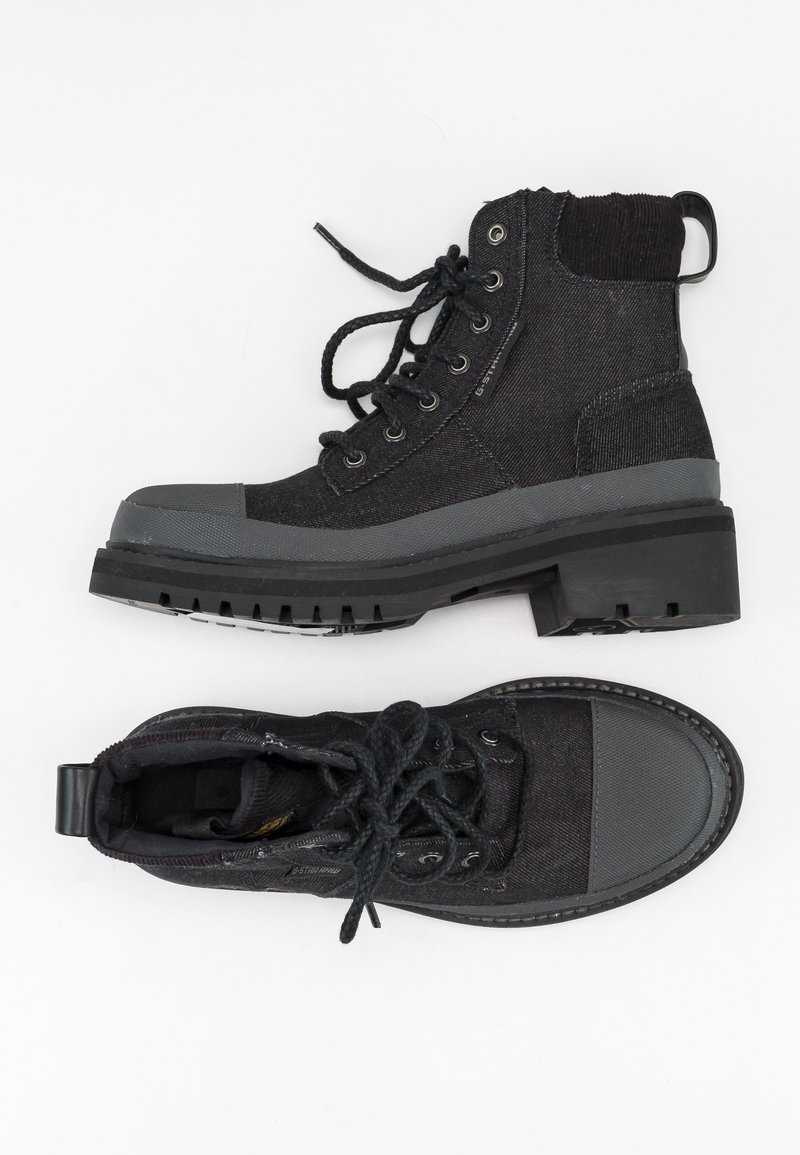 Bottines noires présentant des matériaux en tissu et en caoutchouc, bout rond, design à lacets et accents texturés. Comprend une semelle plate pour plus de stabilité.