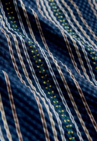 Blue fabric with vertical stripes in white, brown, and green, featuring small yellow floral patterns, shown with soft folds and texture.