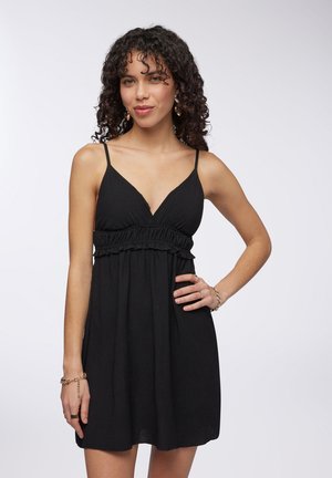 Abito nero con scollatura a V, spalline sottili e vita arricciata, realizzato in tessuto testurizzato, lunghezza al ginocchio, con vestibilità comoda.