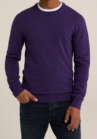 Lila tröja i ett mjukt stickmaterial, med rund halsringning och ribbade ärmslut och nederkant, tillsammans med mörka jeans.