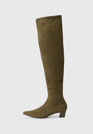 Olive green over-the-knee boots made of soft suede, featuring a pointed toe and a low, chunky heel. Smooth texture and minimal stitching details.