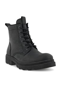 Bottes noires à la cheville en cuir lisse, dotées d'un laçage à l'avant, d'une semelle en caoutchouc robuste et d'une languette à l'arrière. Fini texturé.
