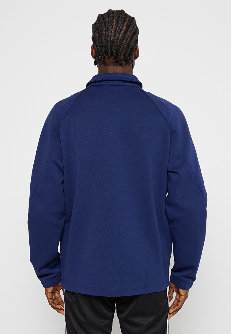 Dunkelblauer Pullover mit hohem Kragen, Raglanärmeln und gerippten Bündchen. Weiche Textur und entspannte Passform ohne sichtbare Logos.