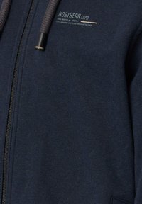 Navy Zip-Hoodie aus weichem Stoff, mit Kapuze mit Kordelzug, silbernen Applikationen und gesticktem "NORTHERN EXPO"-Logo auf der Brust.
