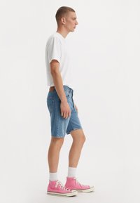 Denim shorts in light blue, relaxed fit, with a simple design. Paired with a plain white t-shirt and pink high-top sneakers.