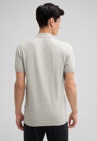 Helles graues Kurzarm-Polohemd mit weicher Textur, geripptem Kragen und Bündchen, gerade geschnittenem Saum und minimalistischem Design.