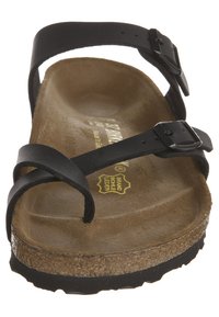 Sandal de cuero negro con dos correas ajustables, una plantilla de corcho y una suela de goma texturizada. La plantilla está contorneada para mayor comodidad.