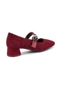Zapato burdeos de tacón bajo con puntera redondeada y una correa decorativa que cuenta con una hebilla metálica, fabricado en un material suave similar a gamuza.