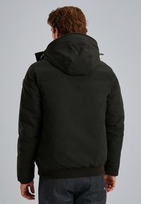 Giacca nera imbottita con cappuccio, dotata di chiusura zip e polsi elasticizzati. Texture morbida, progettata per calore e comfort.