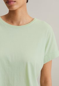 Helle grüne, kurzärmelige T-Shirt aus weicher Baumwolle, mit rundem Ausschnitt und umgeschlagenen Ärmeln, glatter Textur und simplem Design.