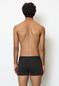 Boxers en coton noir avec une texture lisse, une taille élastique et un design à jambes courtes, présentés de dos.
